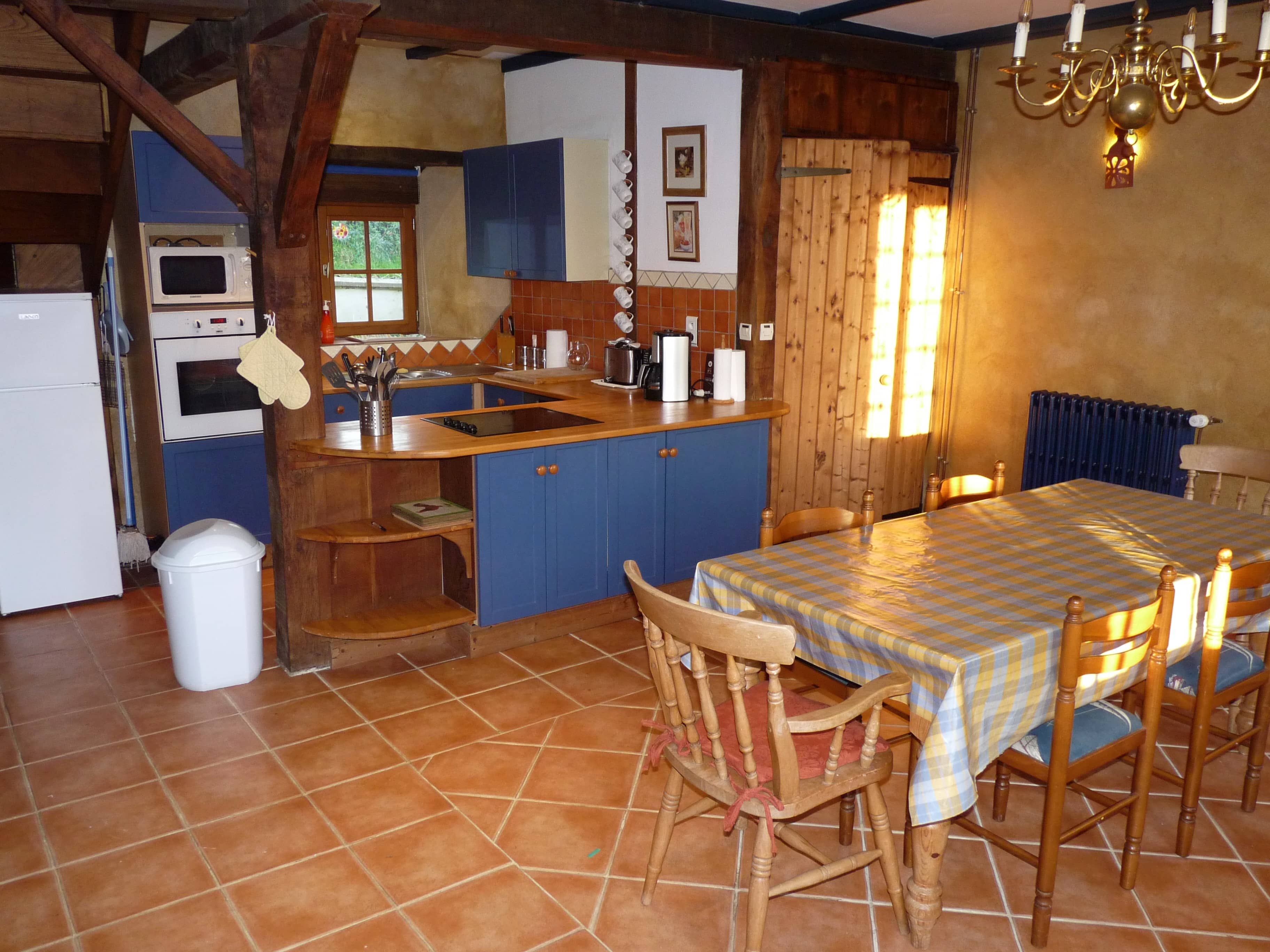 Kitchen of La Julerie cottage in Brittany, France, with a dining table, high-end appliances, and a view of the garden. Ideal for preparing holiday meals with family or friends.